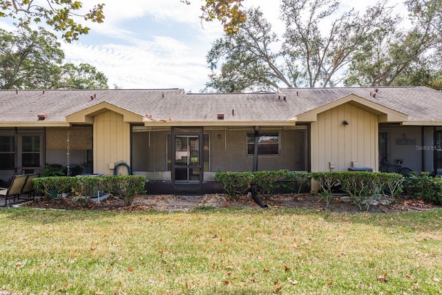 ranch-style house with a sunroom, roof with shingles, and a front yard