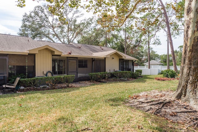 rear view of property with a sunroom, fence, and a lawn