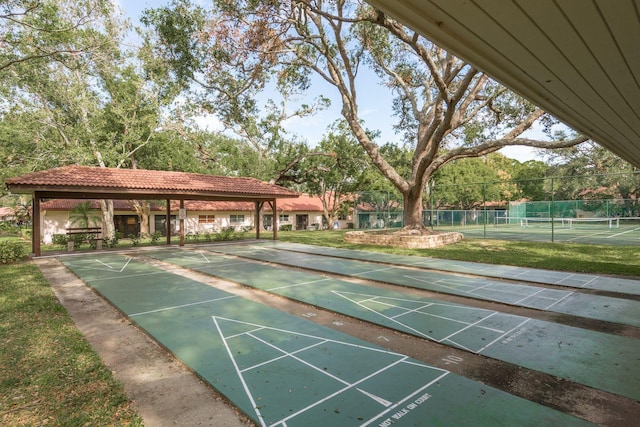 view of home's community with fence and shuffleboard