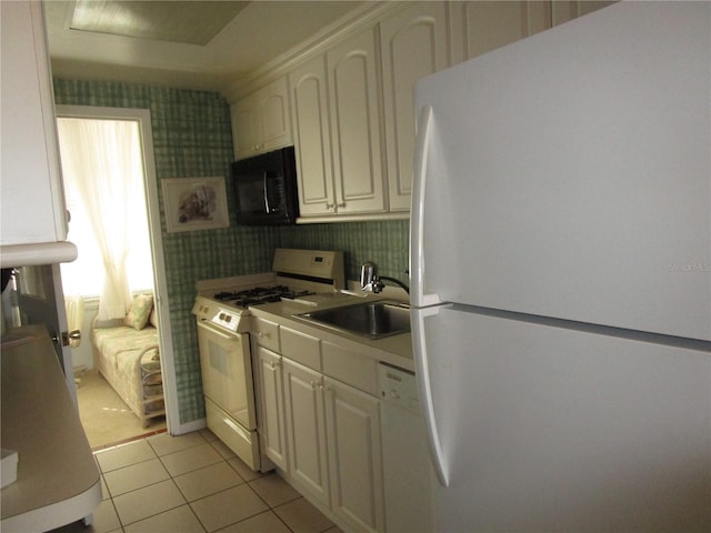 kitchen featuring cream cabinets, sink, white appliances, and light tile patterned flooring