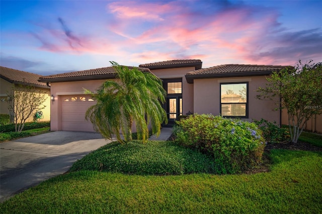 mediterranean / spanish-style house with a garage and a lawn