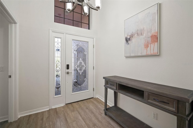 foyer entrance with light hardwood / wood-style flooring and a chandelier