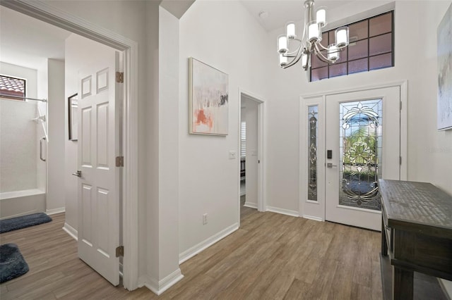 foyer with hardwood / wood-style flooring, a high ceiling, and an inviting chandelier