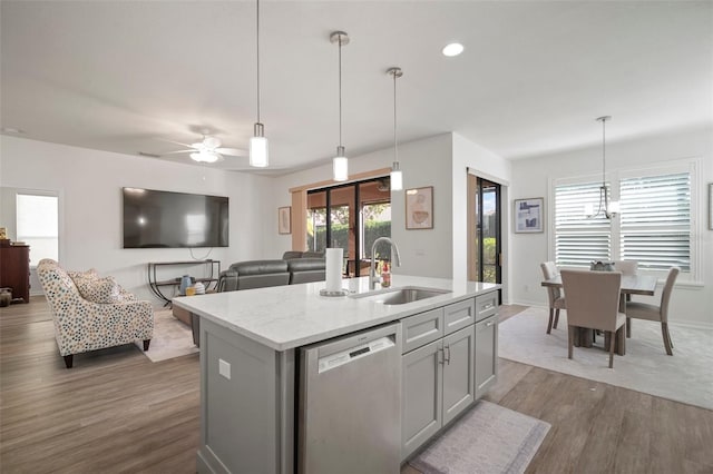 kitchen featuring a center island with sink, sink, dark hardwood / wood-style floors, decorative light fixtures, and stainless steel dishwasher