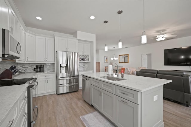 kitchen with stainless steel appliances, a center island with sink, sink, and white cabinetry