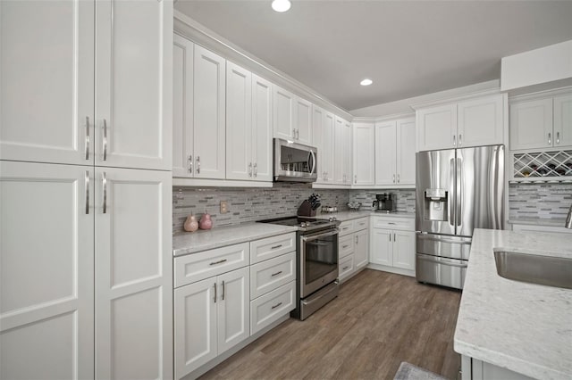 kitchen with white cabinets, appliances with stainless steel finishes, dark wood-type flooring, and backsplash