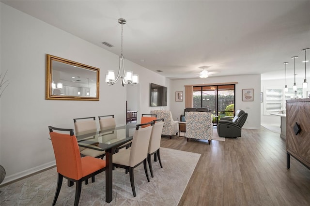 dining room featuring ceiling fan with notable chandelier and hardwood / wood-style flooring