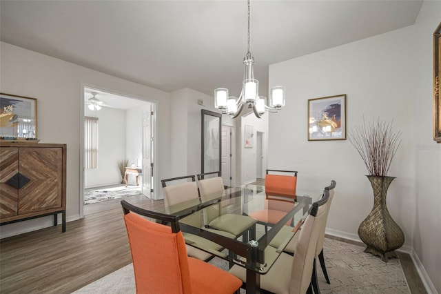 dining space featuring wood-type flooring and ceiling fan with notable chandelier