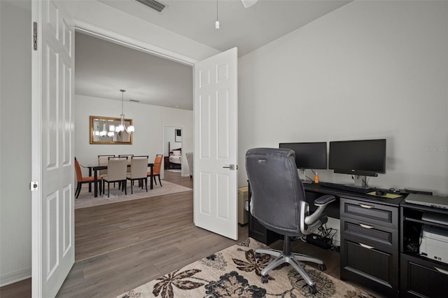 office space featuring wood-type flooring and a notable chandelier