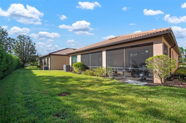 back of property featuring a sunroom, central AC, and a yard