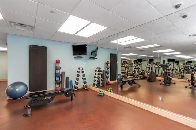 gym featuring a paneled ceiling and concrete floors