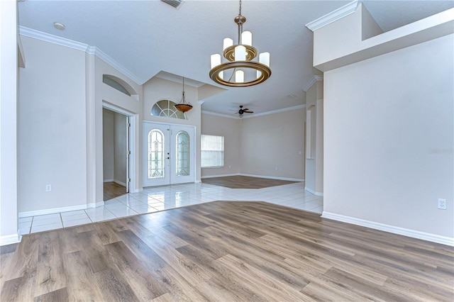 foyer entrance featuring ceiling fan with notable chandelier, a textured ceiling, light wood-type flooring, and ornamental molding