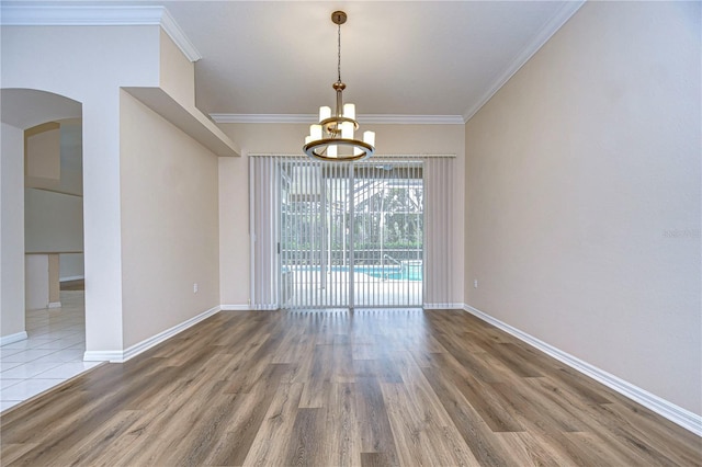 unfurnished dining area with ornamental molding, hardwood / wood-style flooring, and a chandelier