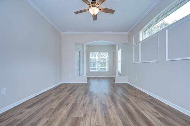 unfurnished room with ornate columns, a wealth of natural light, wood-type flooring, and crown molding