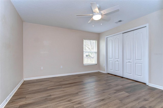 unfurnished bedroom featuring ceiling fan, wood-type flooring, a textured ceiling, and a closet