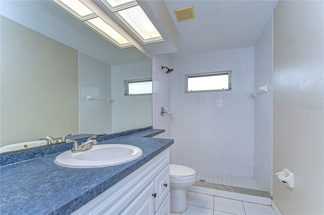 bathroom with tile patterned flooring, tiled shower, toilet, and vanity