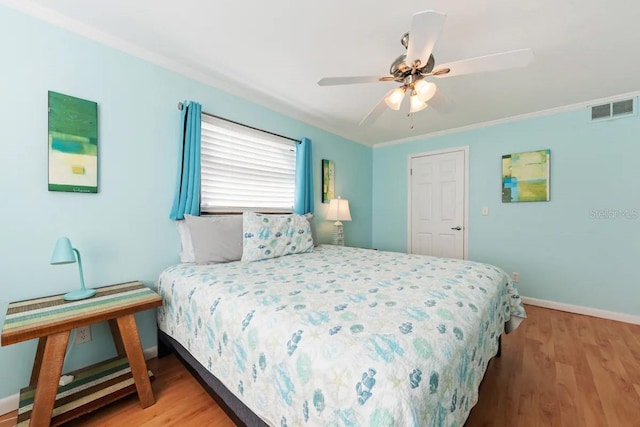 bedroom featuring hardwood / wood-style flooring, ceiling fan, and ornamental molding