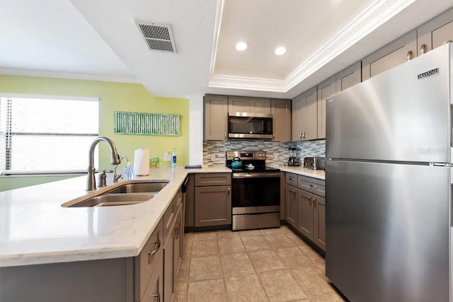 kitchen featuring kitchen peninsula, sink, a raised ceiling, backsplash, and appliances with stainless steel finishes