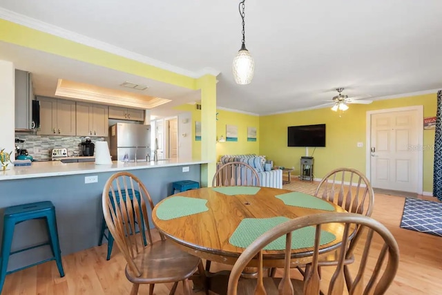 dining space with ceiling fan, light hardwood / wood-style flooring, and ornamental molding