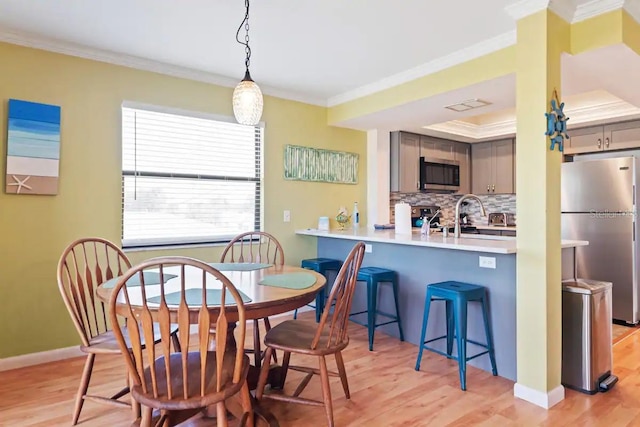 dining room with sink, light hardwood / wood-style floors, and crown molding