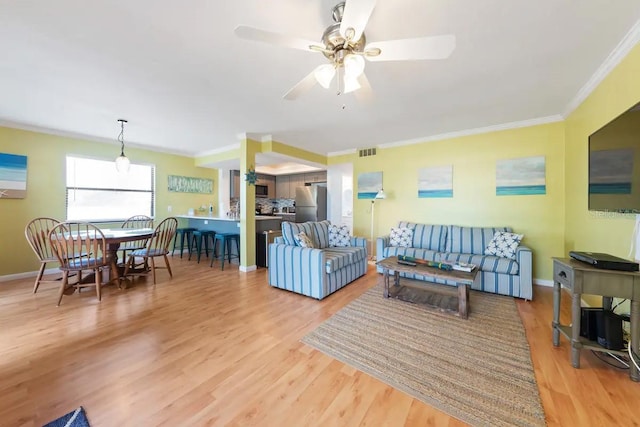 living room featuring hardwood / wood-style flooring, ceiling fan, and crown molding