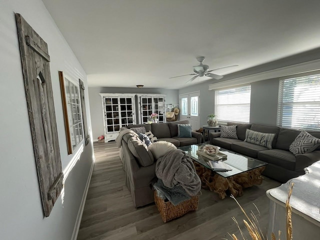 living room with ceiling fan, baseboards, and wood finished floors