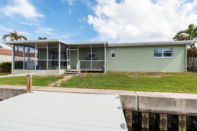 rear view of property featuring a deck, a sunroom, and a yard