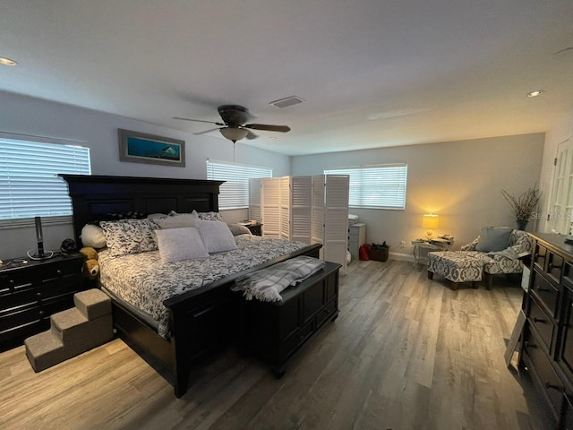 bedroom with ceiling fan, visible vents, baseboards, and wood finished floors