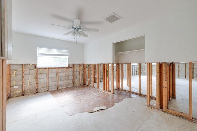 spare room featuring concrete block wall, visible vents, and ceiling fan