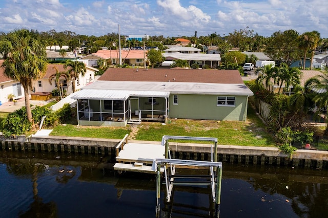 back of house featuring a water view, a lawn, and boat lift