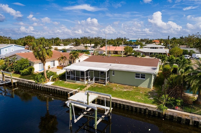 rear view of house featuring a residential view, a water view, a lawn, and boat lift