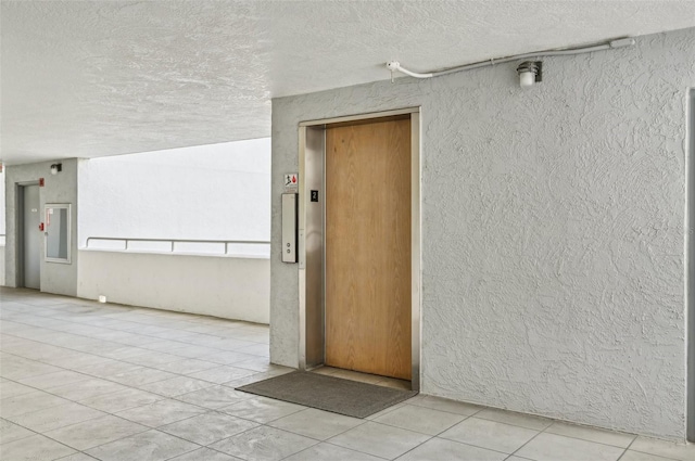 interior space with light tile patterned floors, a textured ceiling, and elevator