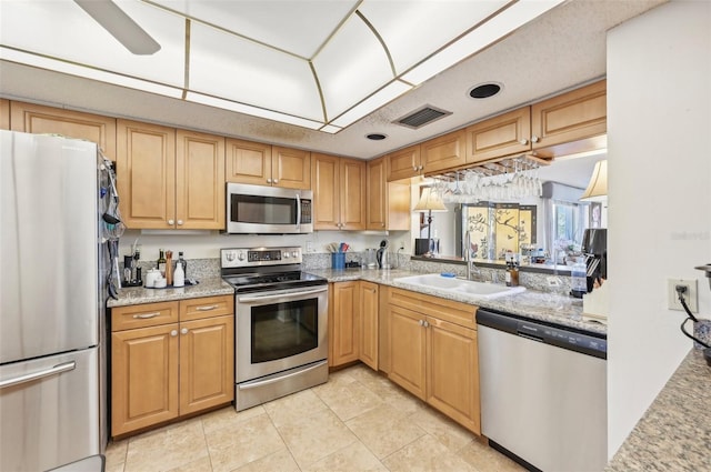 kitchen with light stone countertops, sink, light tile patterned flooring, and stainless steel appliances