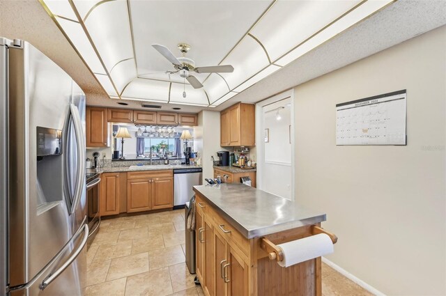 kitchen with stainless steel appliances, ceiling fan, a tray ceiling, and sink