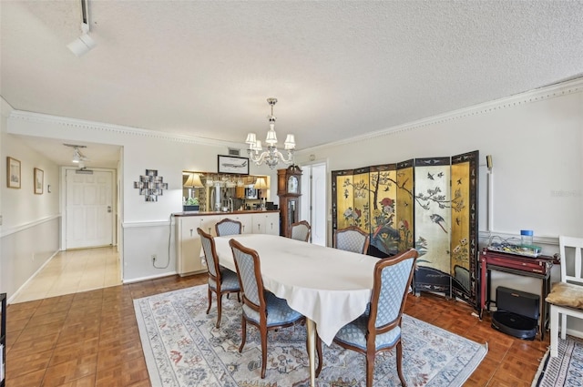 dining area with a notable chandelier, ornamental molding, and a textured ceiling