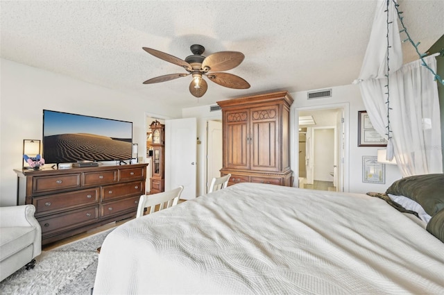 bedroom with hardwood / wood-style floors, ceiling fan, and a textured ceiling