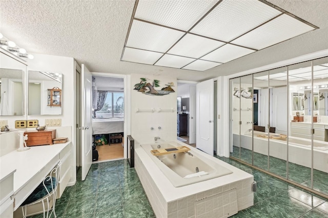 bathroom with a textured ceiling, vanity, and a tub