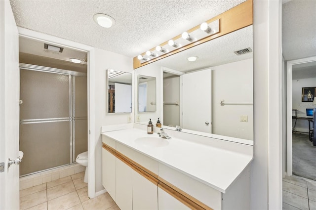 bathroom with vanity, a shower with door, tile patterned floors, toilet, and a textured ceiling