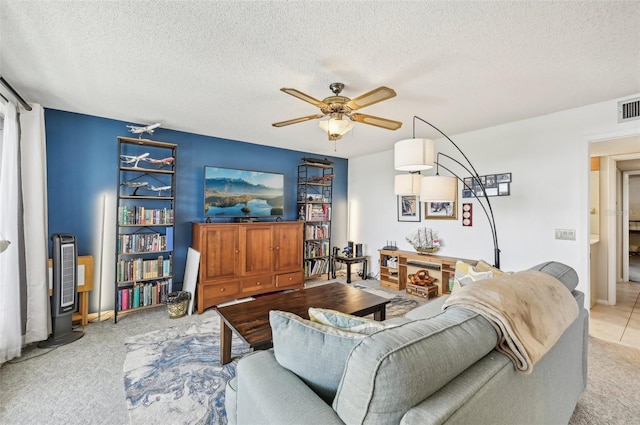 living room with ceiling fan, light carpet, and a textured ceiling