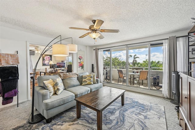 carpeted living room featuring ceiling fan and a textured ceiling