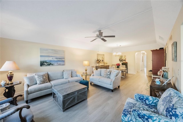 living room with ceiling fan with notable chandelier and light hardwood / wood-style flooring