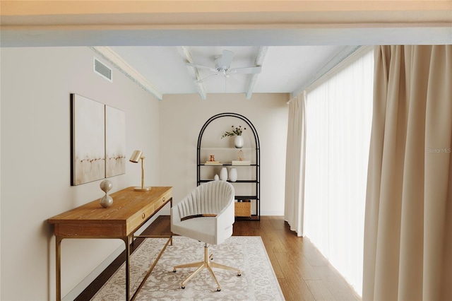 home office with ceiling fan, wood-type flooring, and beam ceiling