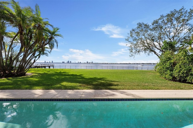 view of swimming pool featuring a water view and a lawn