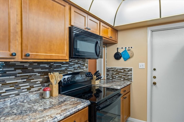 kitchen with black appliances, stone countertops, and tasteful backsplash