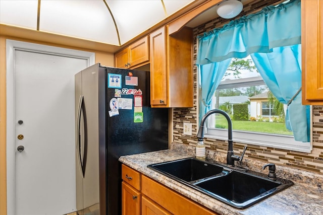 kitchen featuring decorative backsplash, sink, and stainless steel refrigerator