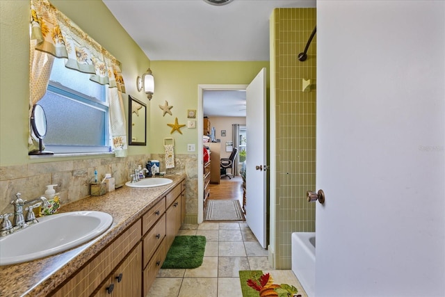 bathroom featuring tiled shower / bath, vanity, tile patterned floors, and tile walls