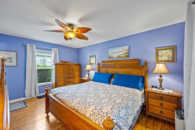 bedroom featuring ceiling fan, hardwood / wood-style floors, and a textured ceiling