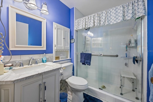 bathroom with tile patterned floors, vanity, toilet, and a shower with door