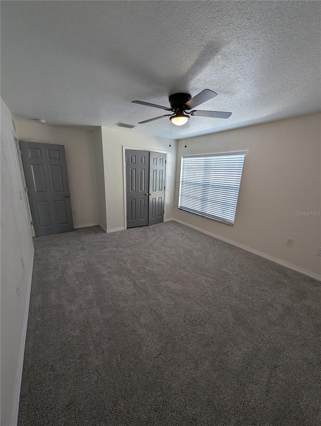 unfurnished bedroom featuring ceiling fan, a textured ceiling, and dark colored carpet