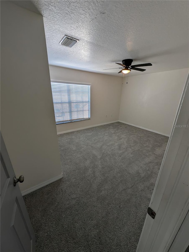 spare room with dark colored carpet, a textured ceiling, and ceiling fan